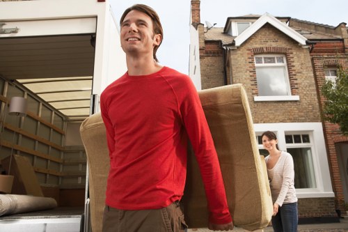 Professional movers carrying household items through a Millwall property